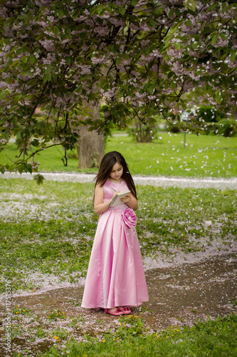 Girl in dress with notebook and pen in garden