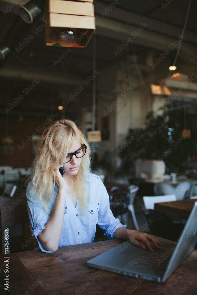 business woman working at a laptop and talking on the phone sitting in a cafe business woman working at a laptop and talking on the phone sitting in a cafe