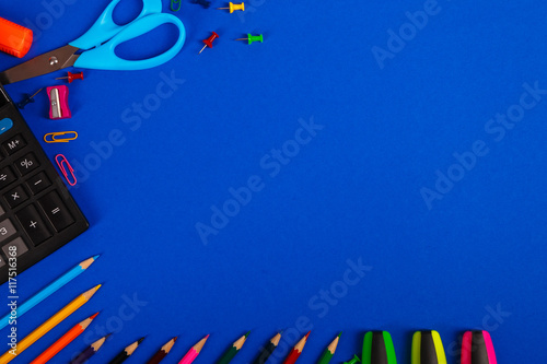 School or office stationery on blue background. Back to School. Frame, copy space. Top view. supplies