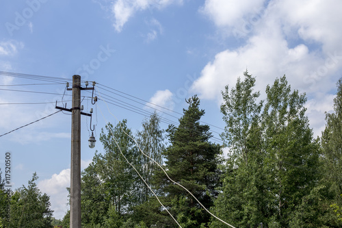 electric pole on the background of trees and blue sky with clouds