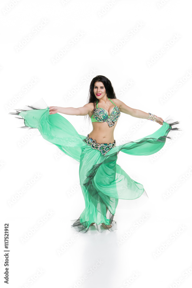 Young beautiful exotic eastern women performs belly dance in ethnic green dress. Isolated on white background Young beautiful exotic eastern women performs belly dance in ethnic green dress. Isolated on white background