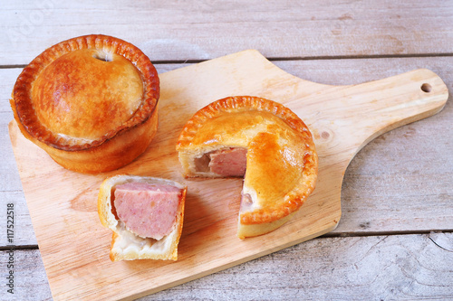 Traditional English pork pie on a wooden cutting board.