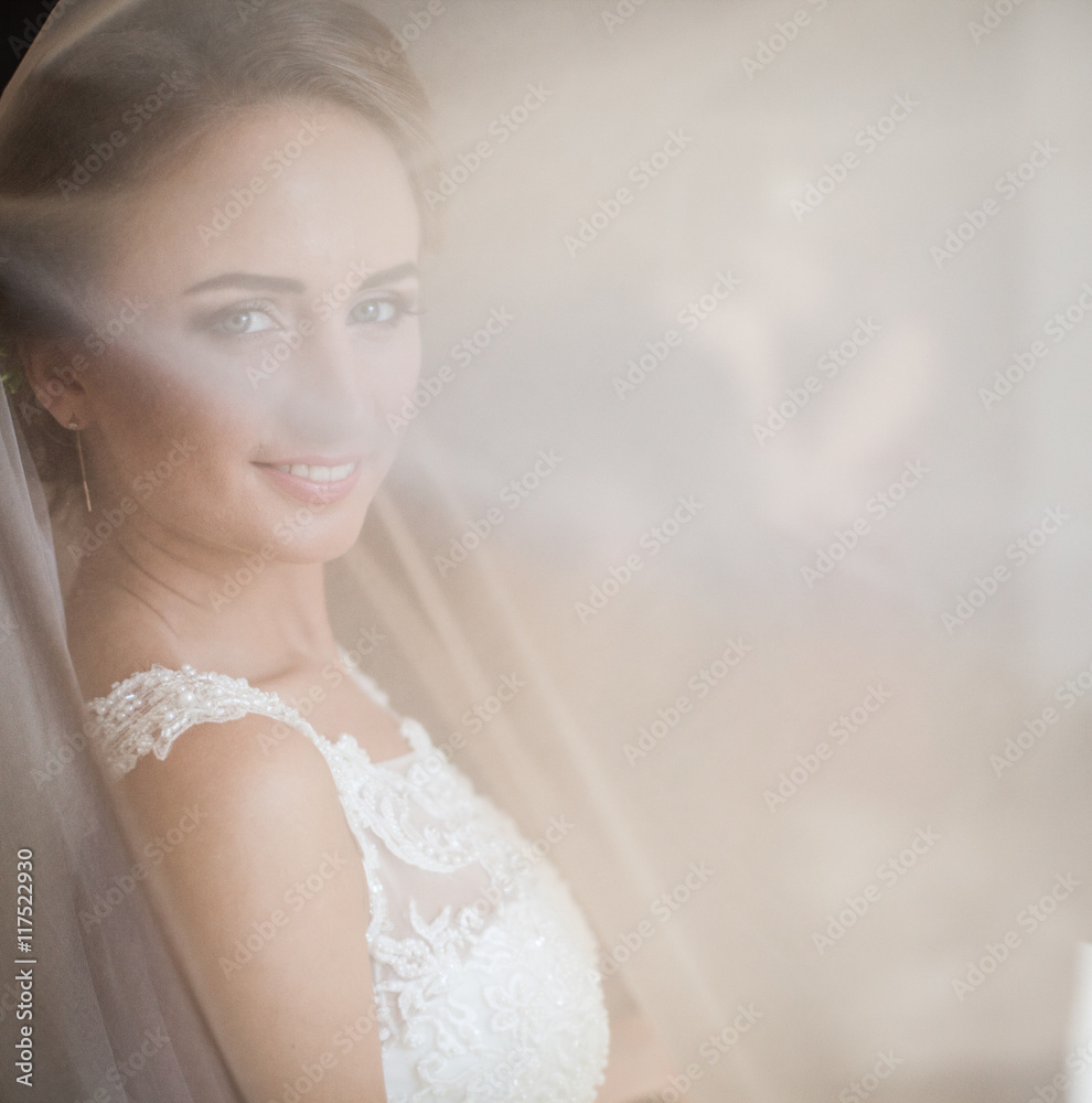 The charming bride stands in the white canvas The charming bride stands in the white canvas