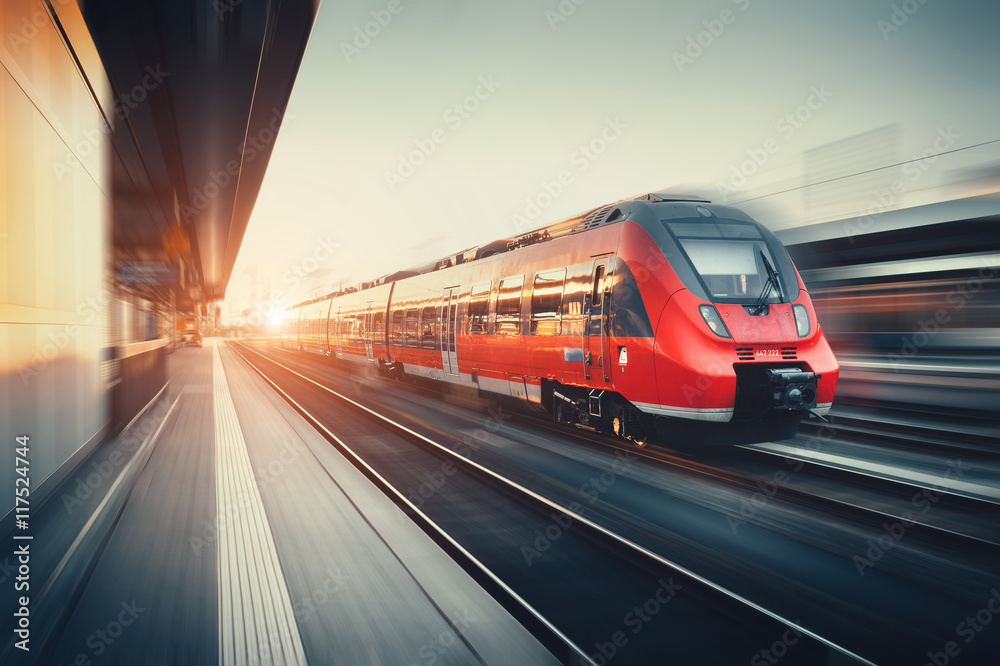 Fototapeta premium Piękna stacja kolejowa z nowoczesnym czerwonym pociągiem pod słońcem