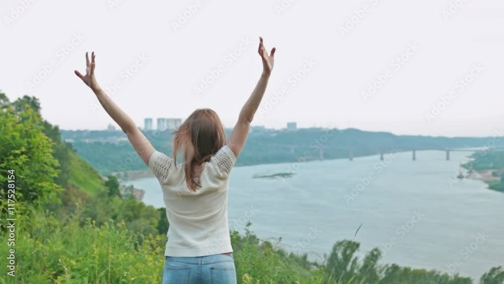Successful woman raising hands near river, concept of freedom Successful woman raising hands near river, concept of freedom