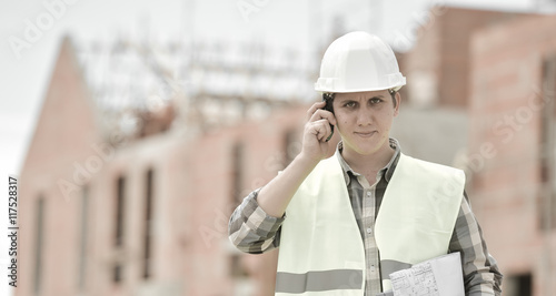 Foreman walking using walkie-talkie on construction site