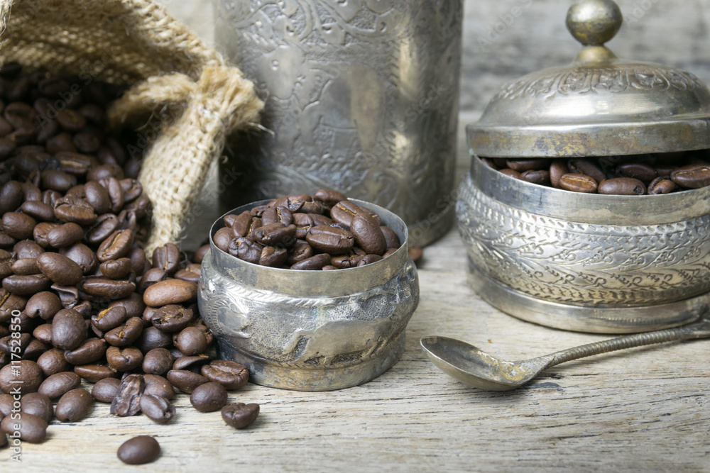 Silver cup and Coffee beans in sackcloth bag on wooden backgroun Silver cup and Coffee beans in sackcloth bag on wooden backgroun