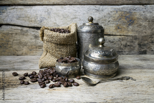 Silver cup and Coffee beans in sackcloth bag on wooden backgroun