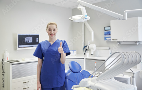 happy female dentist showing thumbs up at clinic
