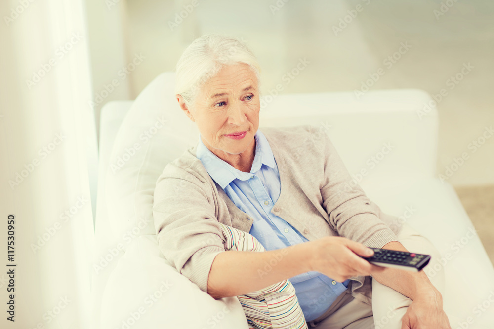 senior woman with remote watching tv at home senior woman with remote watching tv at home