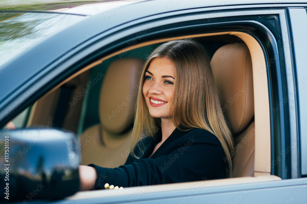Attractive business woman with sunglasses smiling and driving her car.