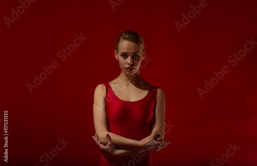 Beautiful expressive dancer in red outfit, studio shot on red background