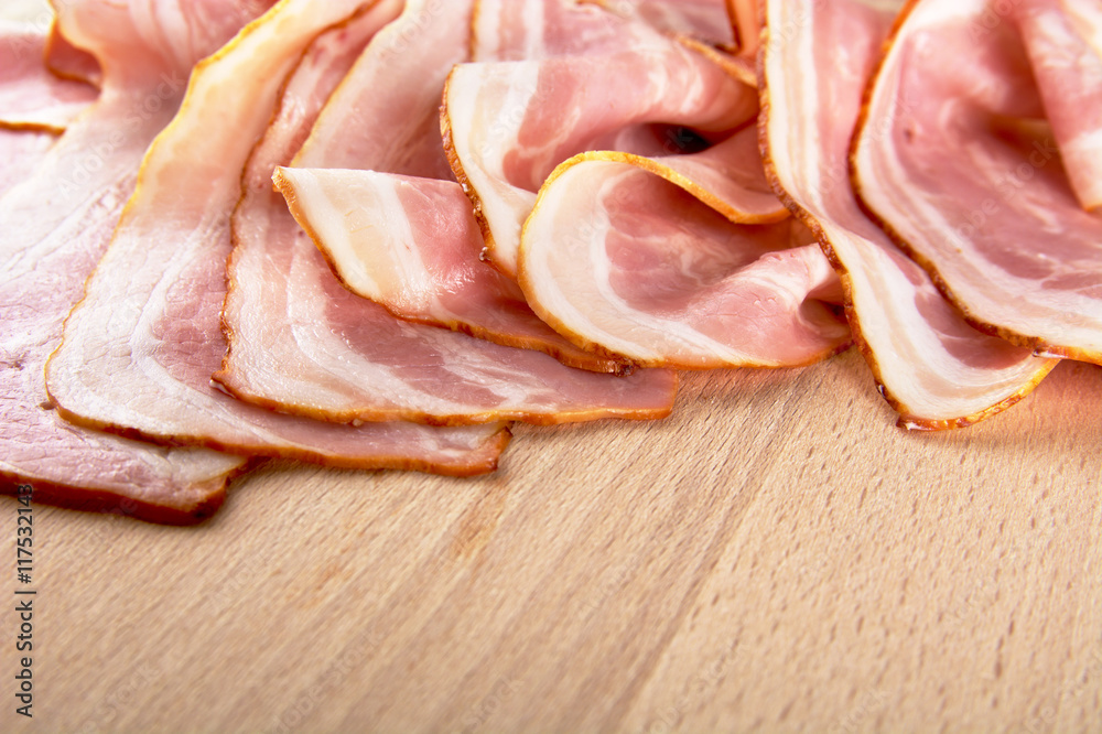 Assorted slices of fat pink bacon on wooden desk Assorted slices of fat pink bacon on wooden desk