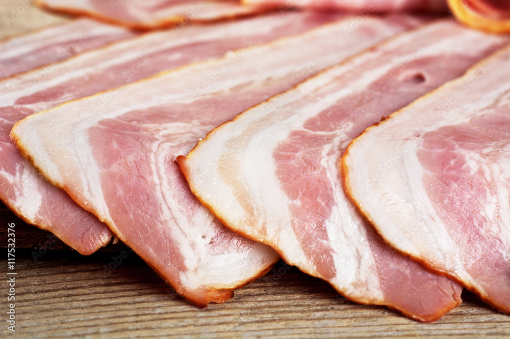 Assorted slices of fat pink bacon on wooden desk Assorted slices of fat pink bacon on wooden desk