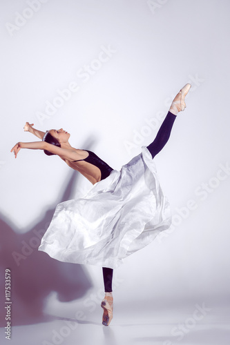 Fototapeta Naklejka Na Ścianę i Meble -  Ballerina in black outfit posing on toes, studio background.
