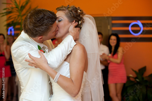 A passionate kiss between newlyweds standing in an orange dance