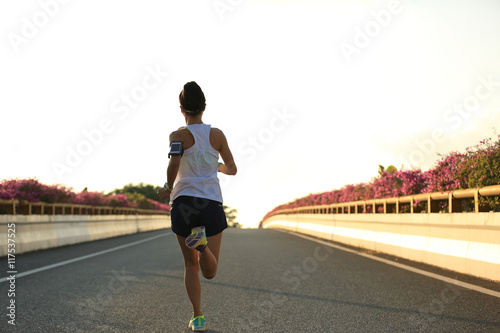 young woman runner running on city bridge road