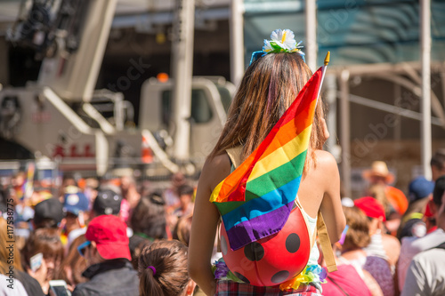 A female spectator with a rainbow flag is watching the gay pride