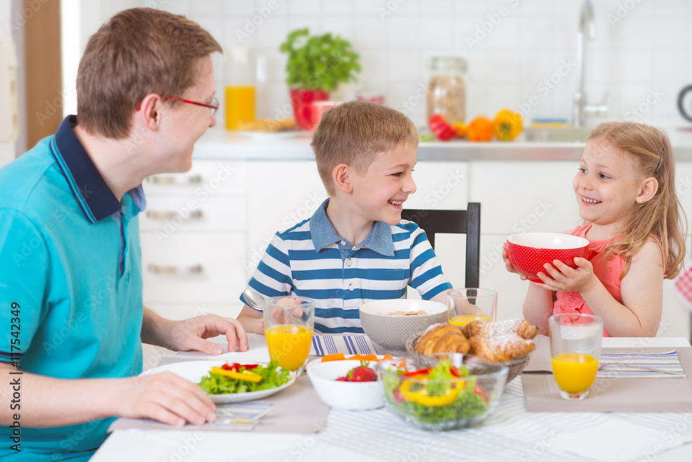 Smiling family eating breakfast in kitchen