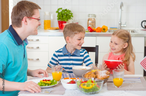 Smiling family eating breakfast in kitchen