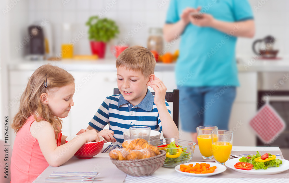 Two happy children eating breakfast during father works Two happy children eating breakfast during father works