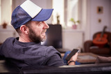 Man on a couch in the living room with a mobile phone looking ba