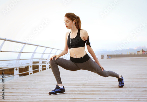 Young woman doing exercises on pier