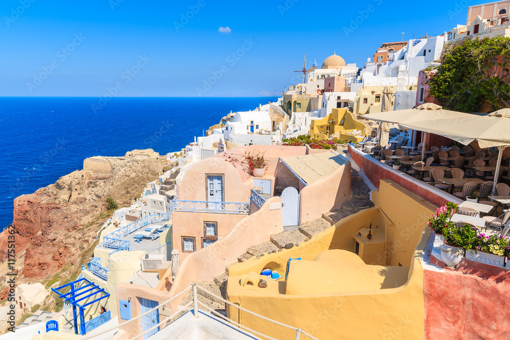 View of famous Oia village with colorful houses and restaurant terrace, Santorini island, Greece