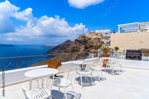 White chairs on terrace and beautiful view of Firostefani village on cliff, Santorini island, Greece.