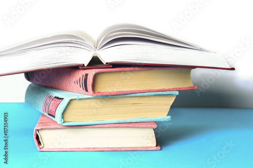 Open book, stack of colorful hardback books on light table. Back © Lyudmyla V