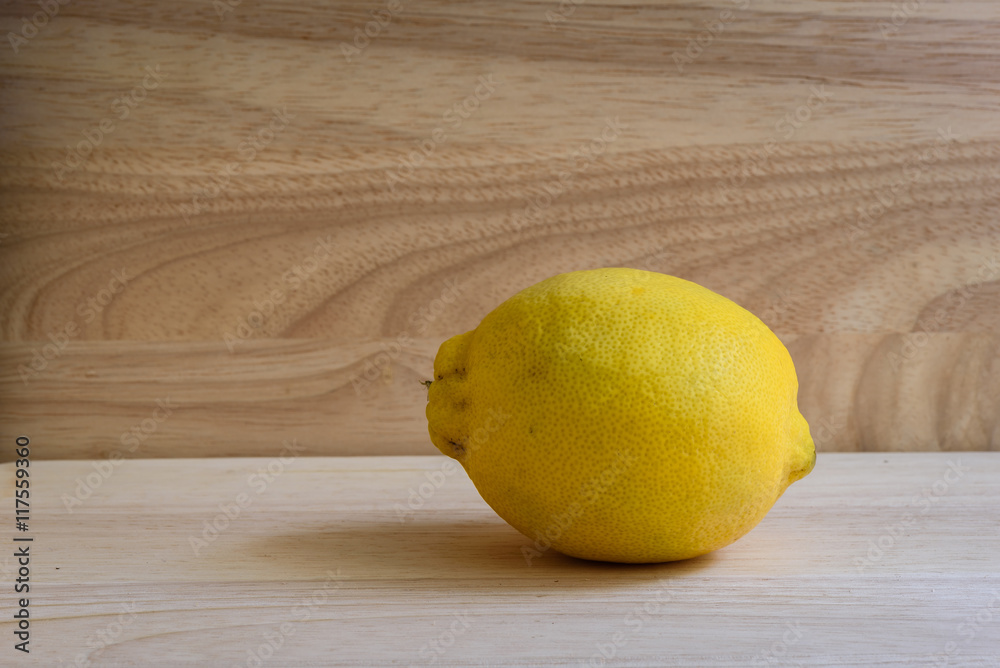 One yellow lemon on wooden background