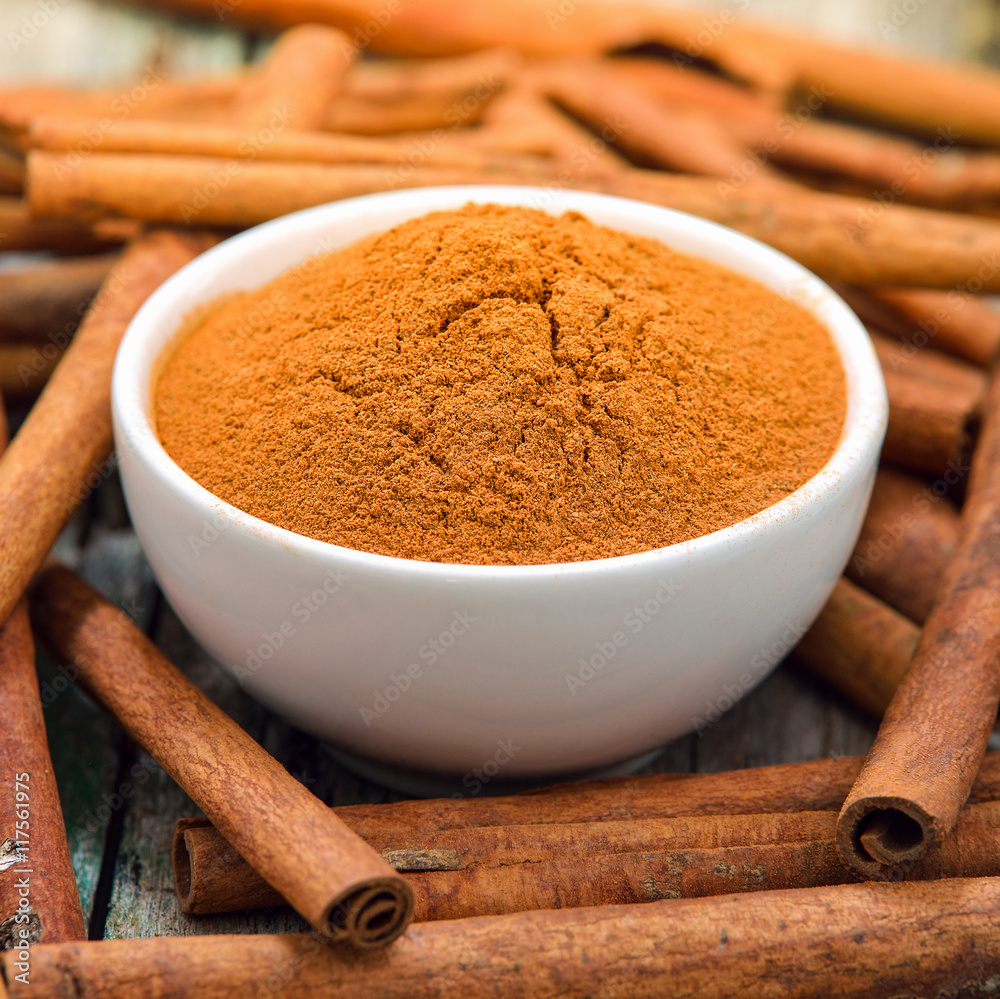 Cinnamon sticks and powder cinnamon in the bowl on table Cinnamon sticks and powder cinnamon in the bowl on table