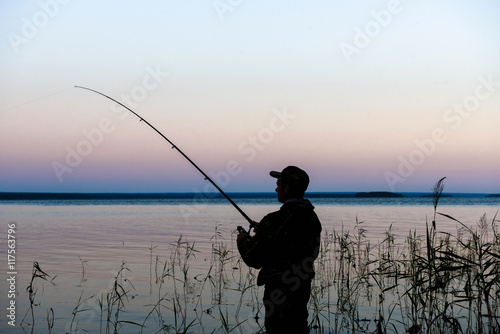 Fisherman silhouette at sunset on the lake while fishing   © river34