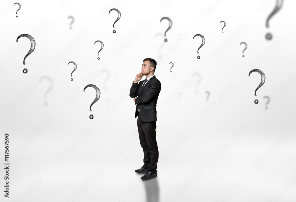 Thoughtful businessman looking upwards surrounded by question marks on white background Thoughtful businessman looking upwards surrounded by question marks on white background