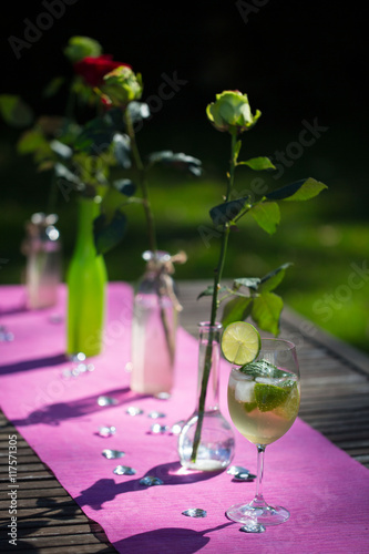 Rosen mit Cocktail auf Gartentisch photo