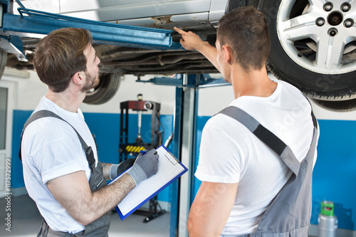 Auto workshop mechanics inspecting damage to car