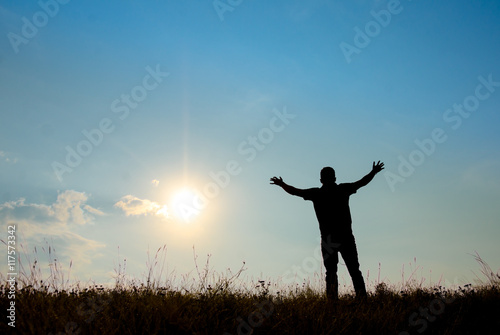 Silhouette of man worship with hands raised to the sky in nature