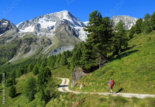 Hiker walking on a gravel road in the beautiful mountains of Arolla, Switzerland. photo