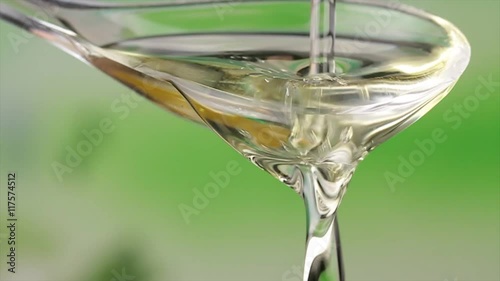 Pours oil on a salad spoon with green background