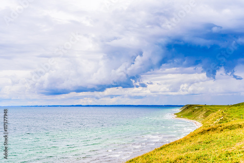 Fototapeta Naklejka Na Ścianę i Meble -  Storm clouds gather over the bay. Steep sandy hills with grass lead up to the grassland above. South coast of Skane, Sweden.