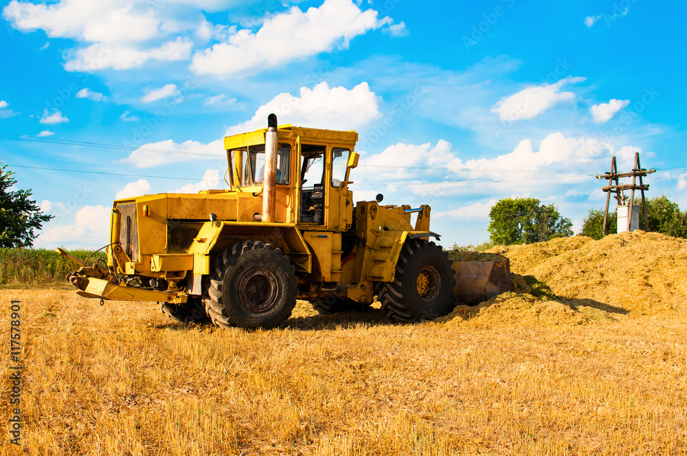 Yellow bulldozer in a field at harvest on a Sunny day Yellow bulldozer in a field at harvest on a Sunny day