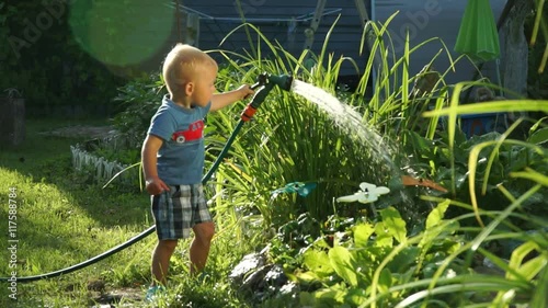 Funny little boy 1.5 years studying hosing plants in the garden
