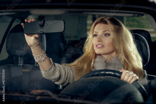 City portrait of pretty blonde driver inside the car. Night scen