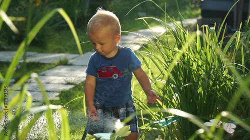 Funny little boy 1.5 years studying hosing plants in the garden