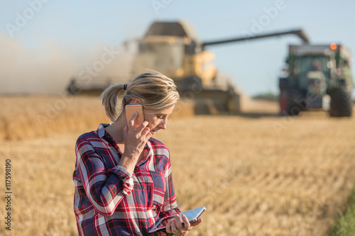 Photography Combine harvester and tractor harvesting wheat in wheatfield