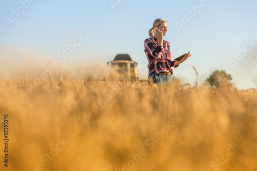 Female farmer walking through field checking wheat crop
