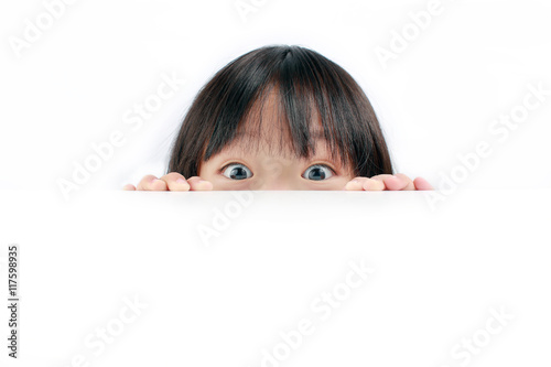 Little Asian girl peeping over white background. photo