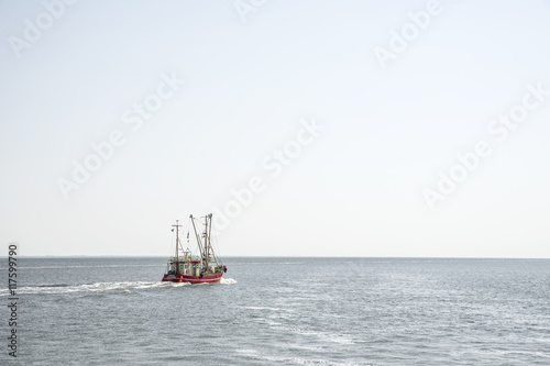 Roter Krabbenkutter verlässt bei stiller See den Hafen der Nordseeinsel Pellworm