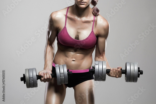 athletic bodybuilder woman with dumbbells.strong girl with muscles training in gym