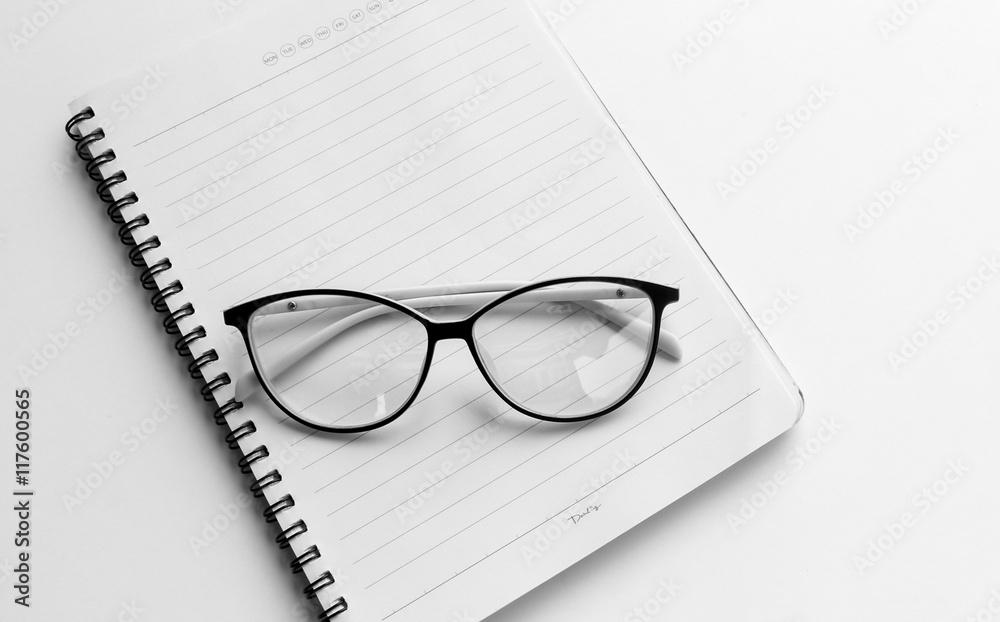 Glassesl on empty white notebook Glassesl on empty white notebook